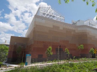 a large brick building against a blue sky with glasshouses on its roof